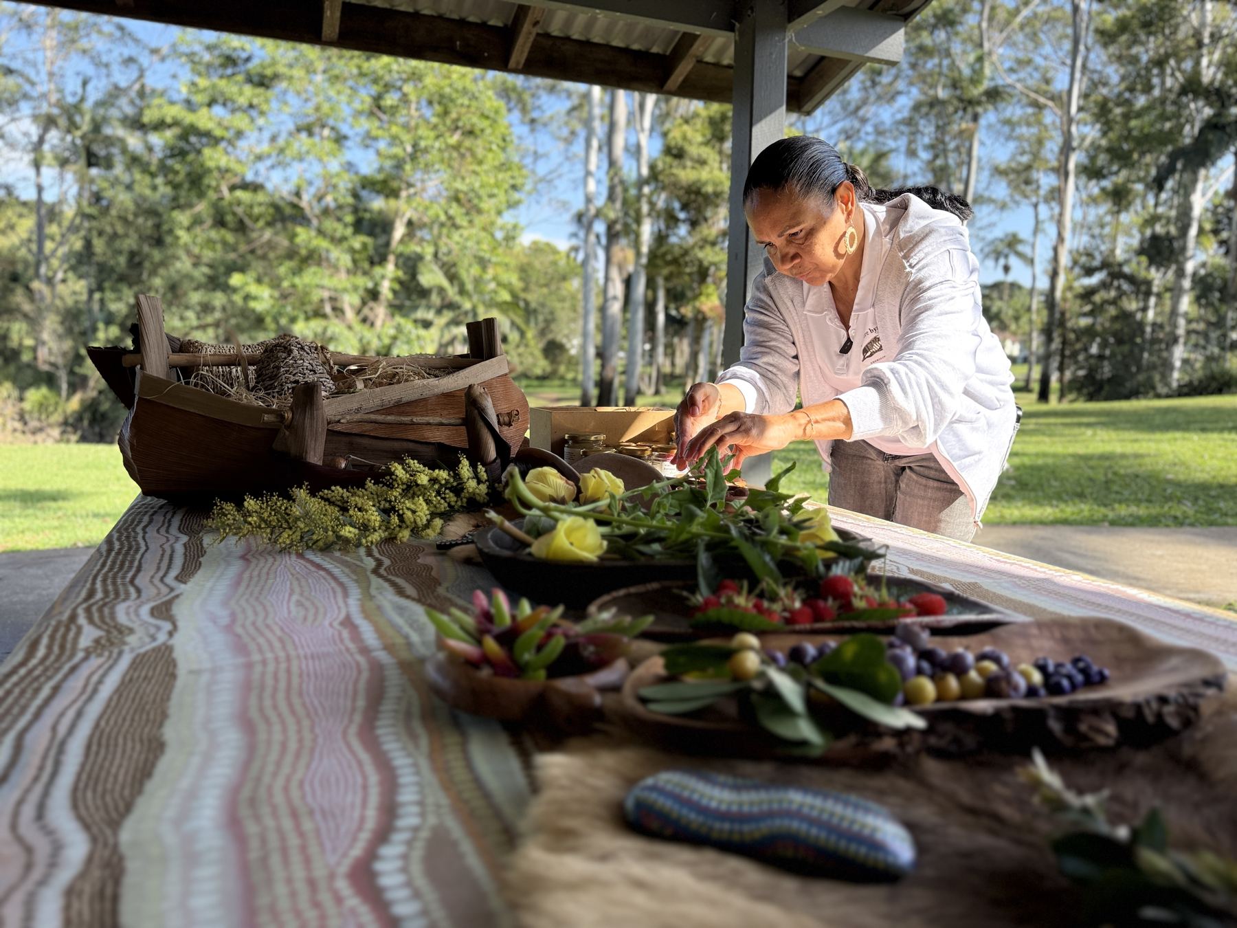 Delta Kay laying out native berries, greens and flowers on a bush food table at Bangalow