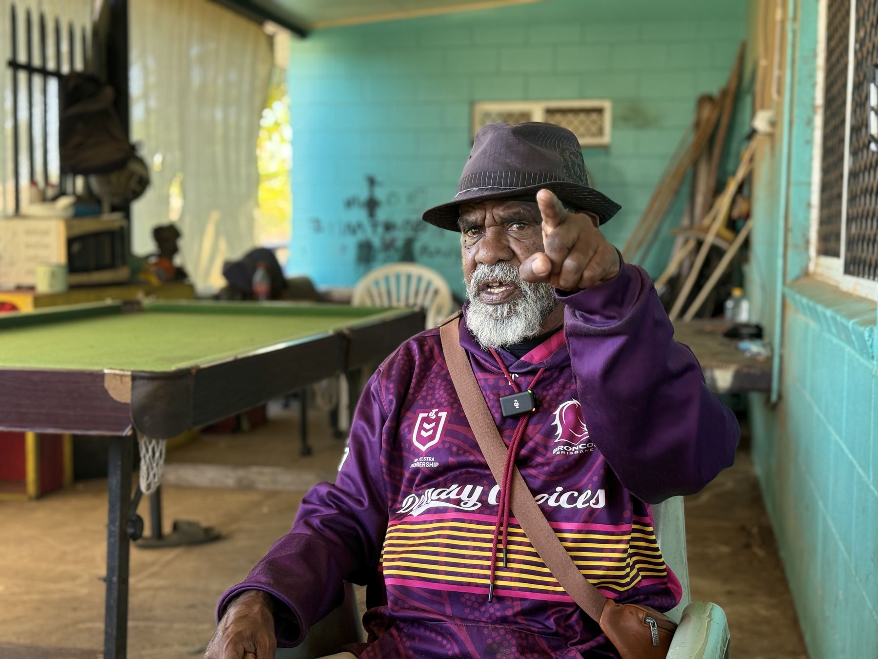 An Elder in a Deadly Choices jersey speaking to camera on a verandah